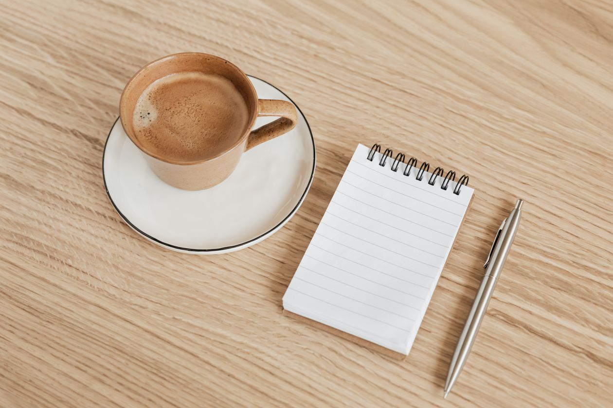 Notebook and coffee on a table for planning a cozy mystery series bible
