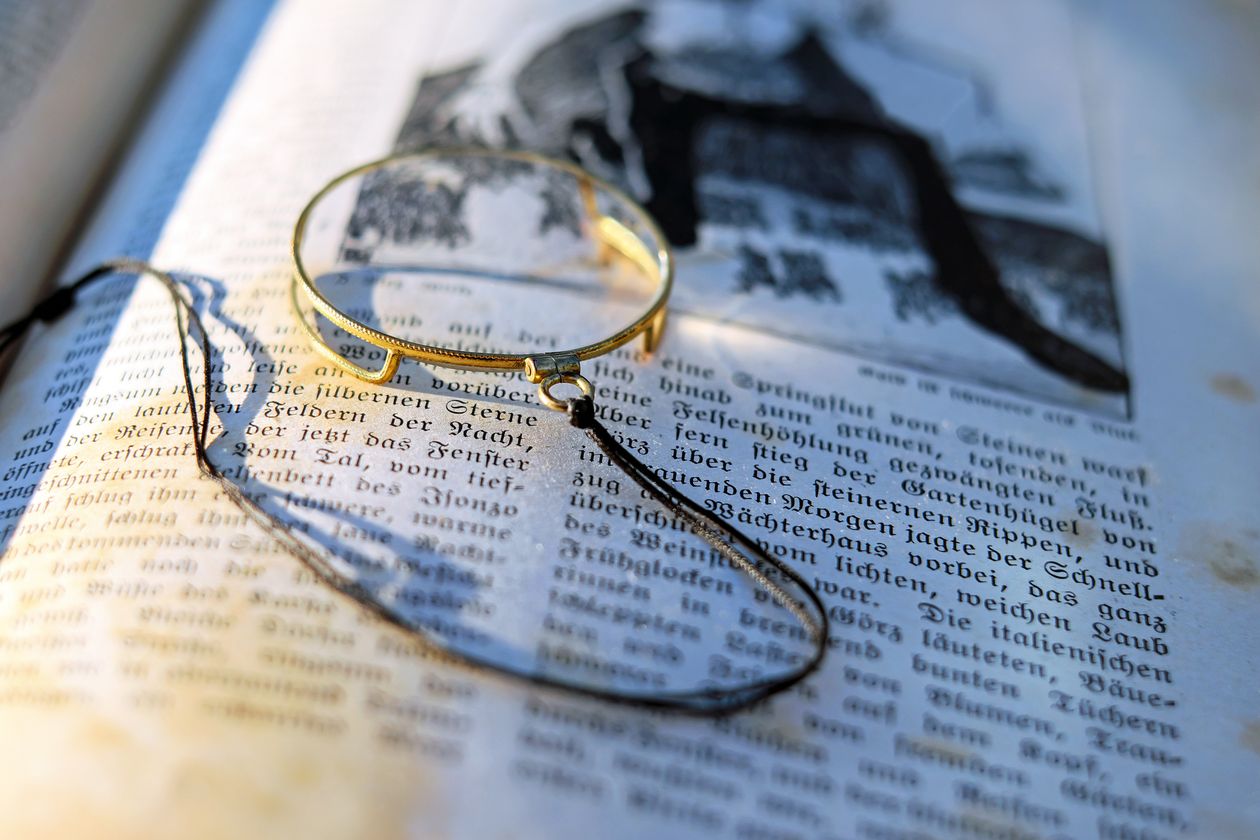 Magnifying glass over an open book, the kind of close look a fair reveal invites