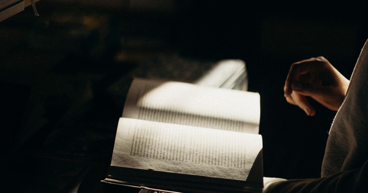 Reader engrossed in a book by warm lamplight, unable to stop turning pages