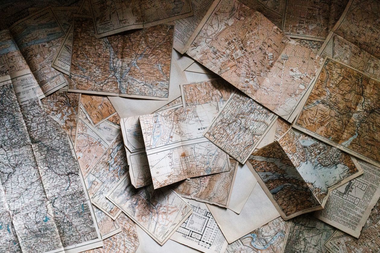 Scattered vintage maps on a table for sketching a fictional town map