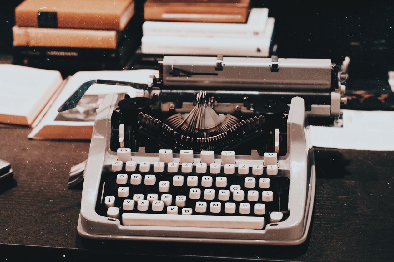 Vintage typewriter on a dark desk beside stacked books