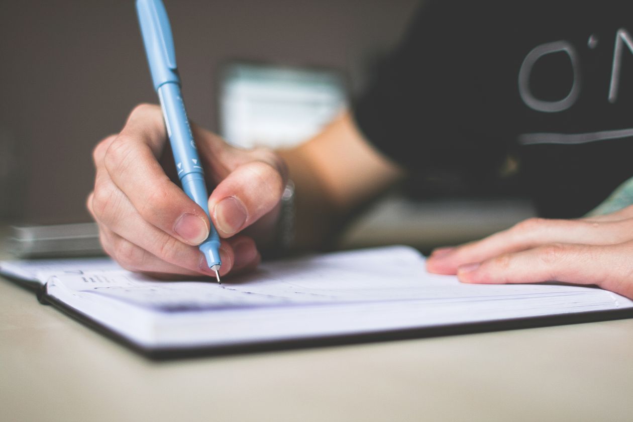 Writer's hand jotting character backstory notes in a notebook